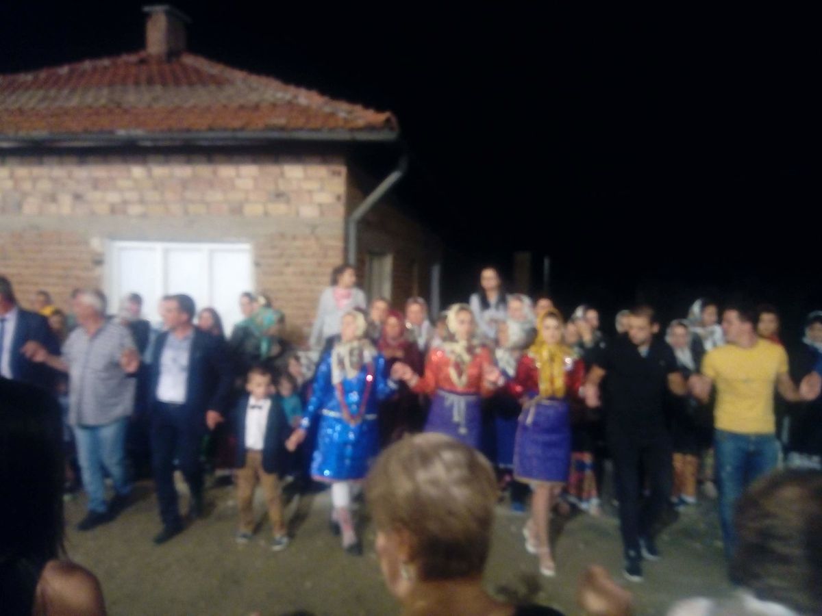 A traditional Bulgarian village wedding, the bride in white with a flower headdress and the groom in a dark suit, framed by family in folk dress